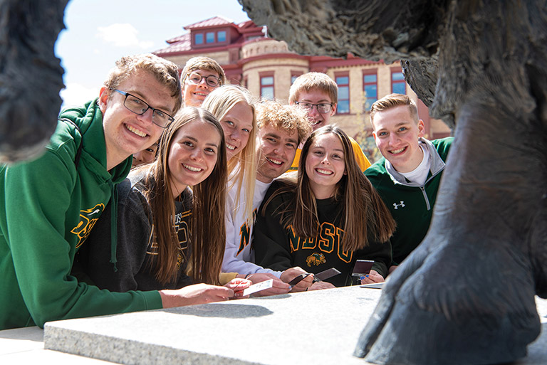 Group of students gathered by NDSU bison statue